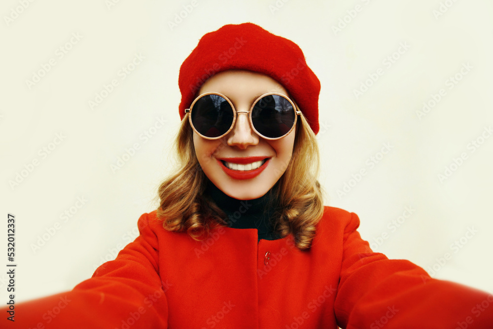Autumn portrait of happy smiling woman stretching hand for taking selfie with smartphone wearing red french beret on background Autumn portrait of happy smiling woman stretching hand for taking selfie with smartphone wearing red french beret on background