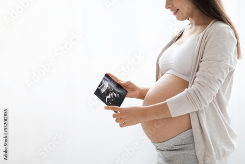 Unrecognizable expecting lady looking at sonogram, copy space