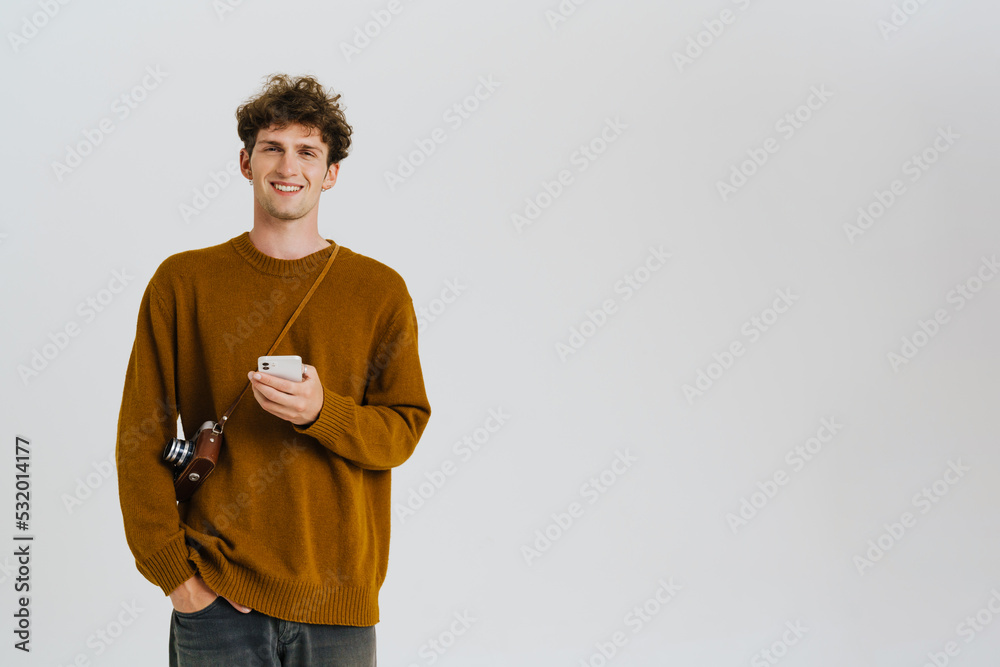 Young handsome curly smiling man in sweater holding phone Young handsome curly smiling man in sweater holding phone