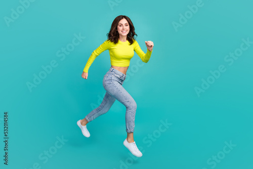 Full size profile portrait of cheerful sportive girl jump running have good mood isolated on teal color background