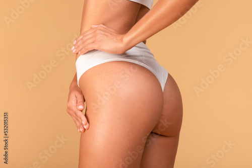 Slim millennial woman in white underwear toucing her hip, satisfied with result of healthy diet or exercising, cropped photo