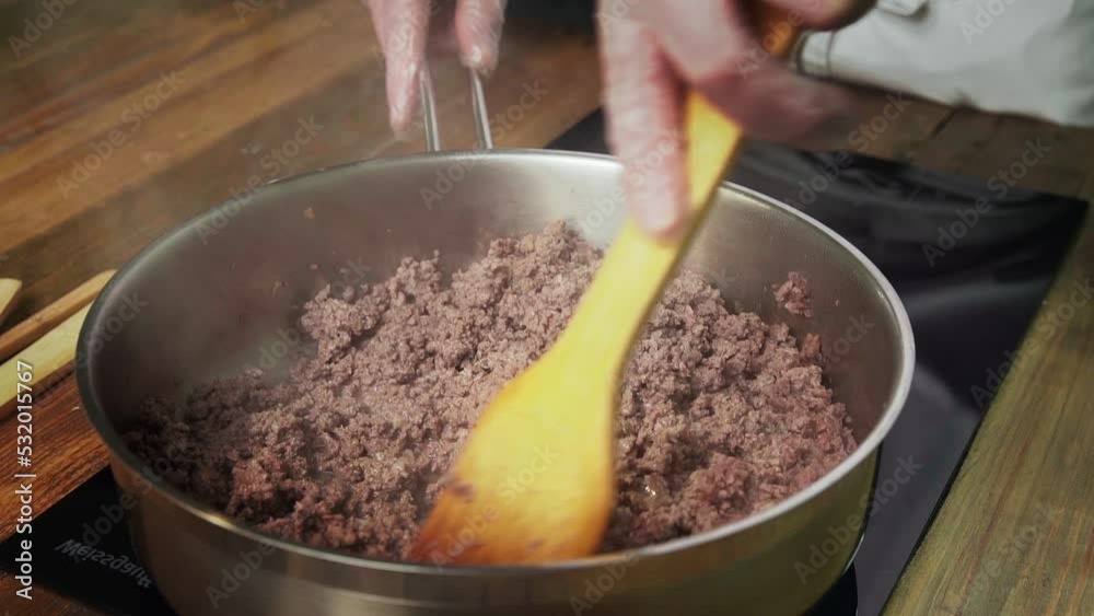 Chef frys chopped meat in a frying pan Chef frys chopped meat in a frying pan