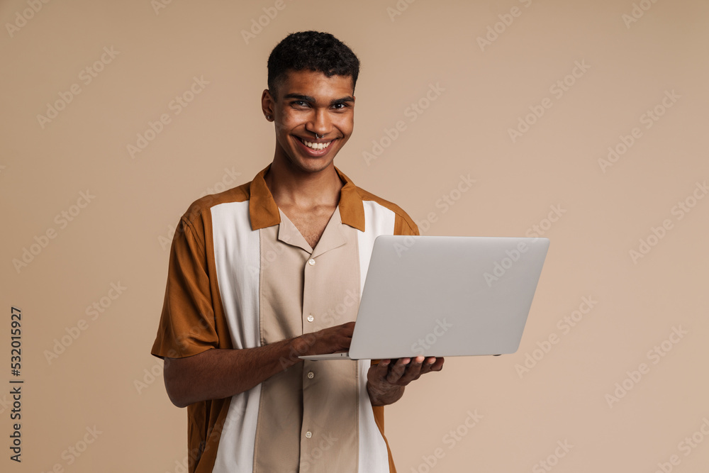 Young handsome smiling african man with piercing holding laptop Young handsome smiling african man with piercing holding laptop