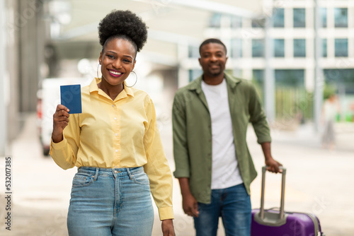 Joyful African Travelers Couple Showing Passport Standing At Airport Outdoors