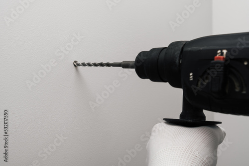 Electric drill making hole in concrete wall.
