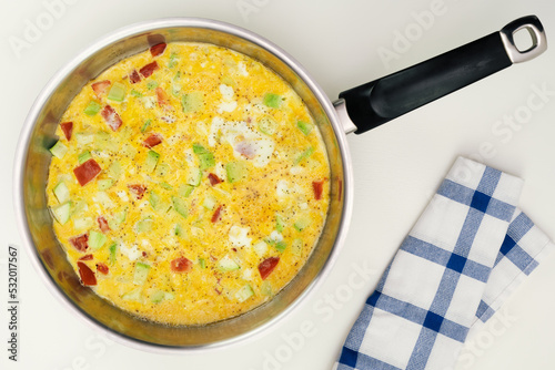 Scrambled eggs with squash and tomato in pan.  Top view.