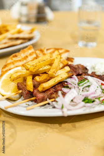 Fried meat souvlaki, fresh vegetables, pita bread, tzatziki sauce and french fries, traditional greek food served in cafe