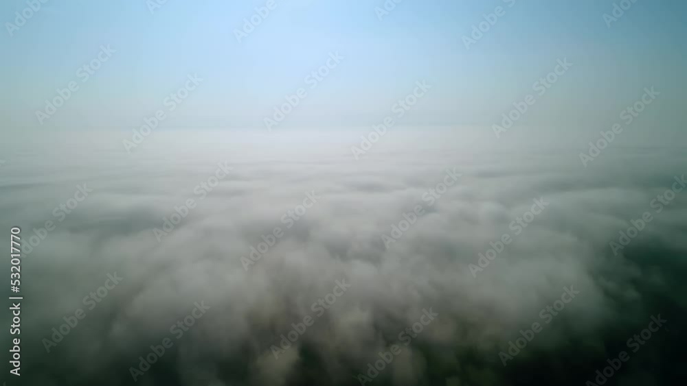 Fast flight over white thick clouds. The horizon divides the blue sky. Aerial view. Fast flight over white thick clouds. The horizon divides the blue sky. Aerial view.