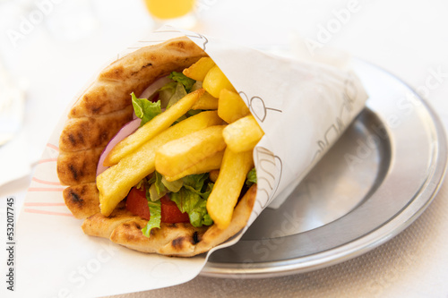 Greek vegetarian gyros with french fries, halloumi cheese and fresh vegetables wrapped in pita and served in greek cafe