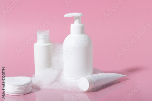 Cosmetics for face, body and hair care. Moisturizer, shampoo or facial cleanser on pink background with foam