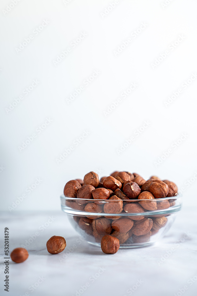 hazelnuts in a bowl on a marble table, space for text, ingredient hazelnuts in a bowl on a marble table, space for text, ingredient