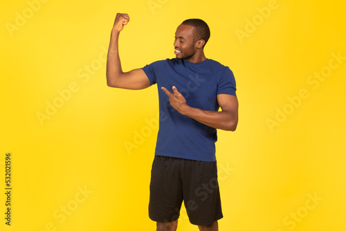 African American Sportsman Showing Biceps Standing Posing Over Yellow Background