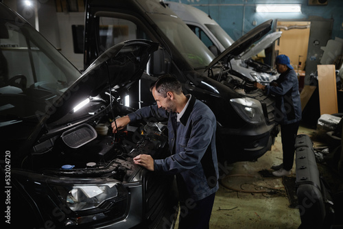 Side view at car mechanics repairing vans and trucks in garage shop or camper factory