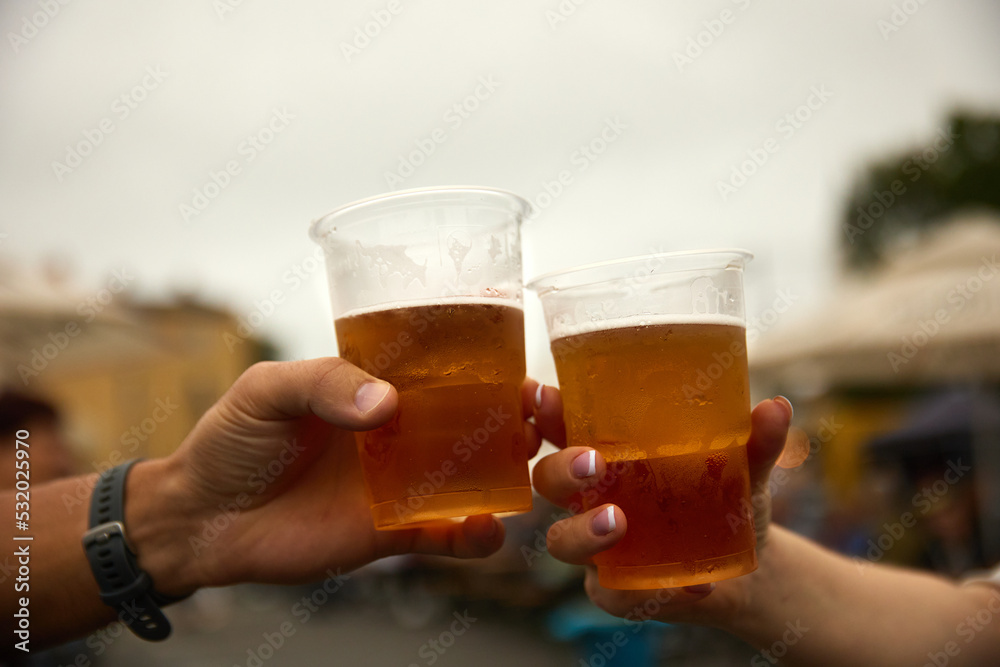 Friends clink glasses with light beer on the street Friends clink glasses with light beer on the street