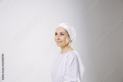 Portrait of a girl in a hijab in white clothes against a white background