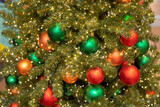 Red and green Christmas balls on a spruce branch close-up, festive New Year card background