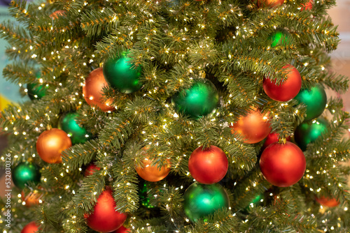 Red and green Christmas balls on a spruce branch close-up, festive New Year card background