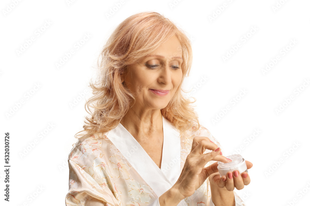Beutiful mature womanin a bathrobe holding a face cream Beutiful mature womanin a bathrobe holding a face cream