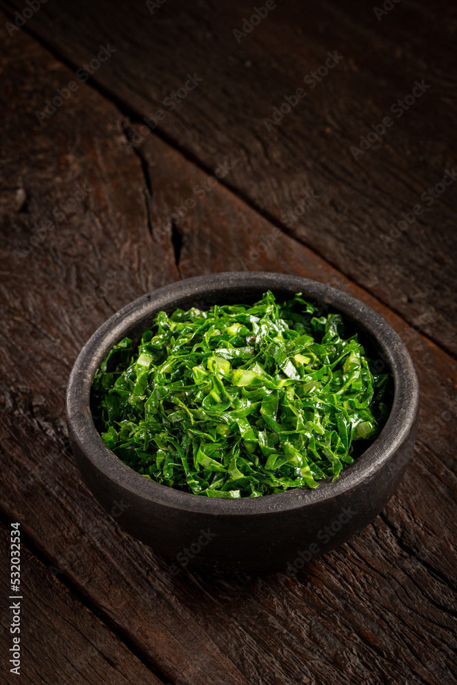 Bowl with chopped green cabbage sautéed in olive oil and garlic. Bowl with chopped green cabbage sautéed in olive oil and garlic.