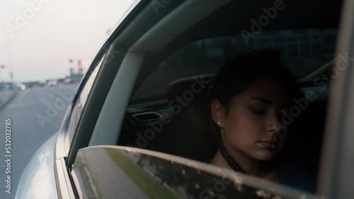 A young beautiful woman rides in a taxi with an open window, looks down at the phone, straightens her hair. Road, trip, car. Slow motion 4k footage