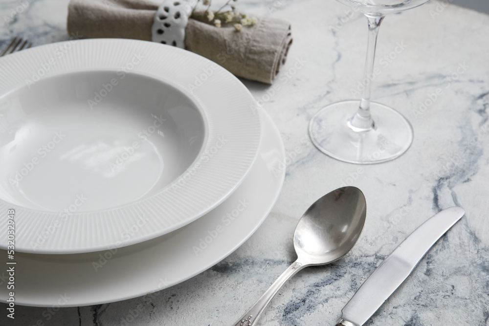 Plates and cutlery on white marble table, closeup