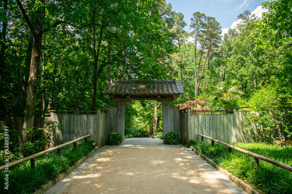 Eastern tori gate with a small child resting on the path leading to a forested garden Eastern tori gate with a small child resting on the path leading to a forested garden