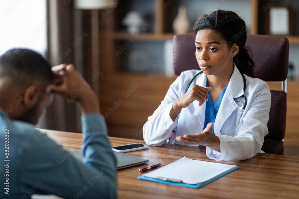 Black woman doctor having conversation with upset sick man patient Black woman doctor having conversation with upset sick man patient