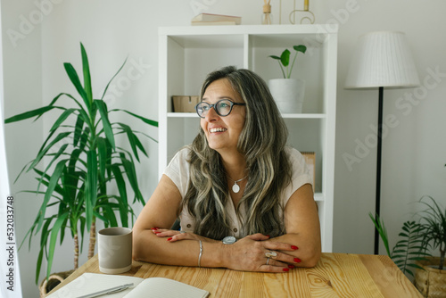 Portrait of cheerful adult businesswoman working from home, she is hawing a break and drinking coffee