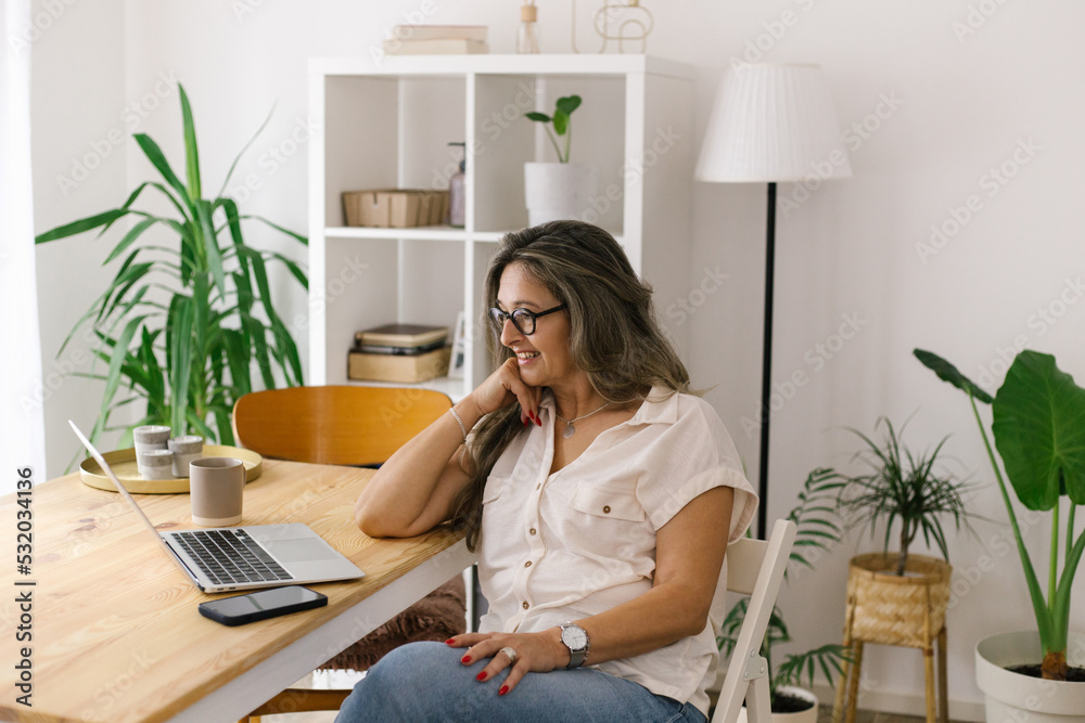 Smiling woman face timing via laptop from home Smiling woman face timing via laptop from home