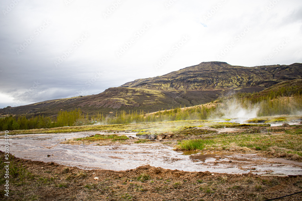 Icelandic geyser with mountain in the background on an overcast day during the summer Icelandic geyser with mountain in the background on an overcast day during the summer