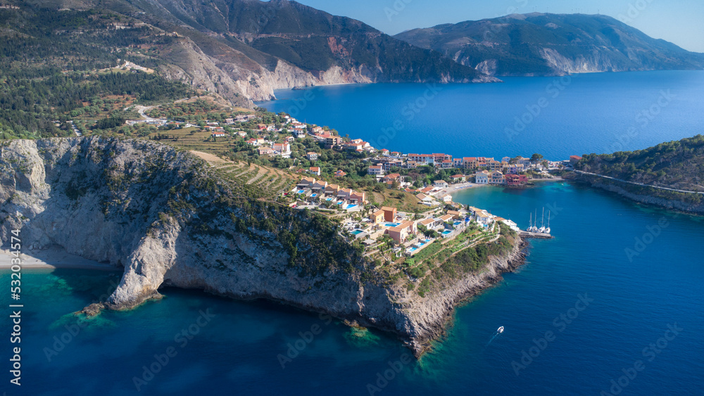 Obraz premium Drone view to beautiful remote town in Greece, surrounded by crystal pacific blue and impressive cliffs on idyllic greek island in Ionian sea