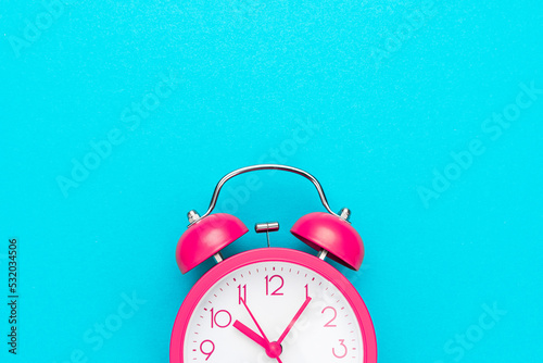 Close up of pink alarm clock over turquoise blue background with copy space. Photo of time management or time is going concept