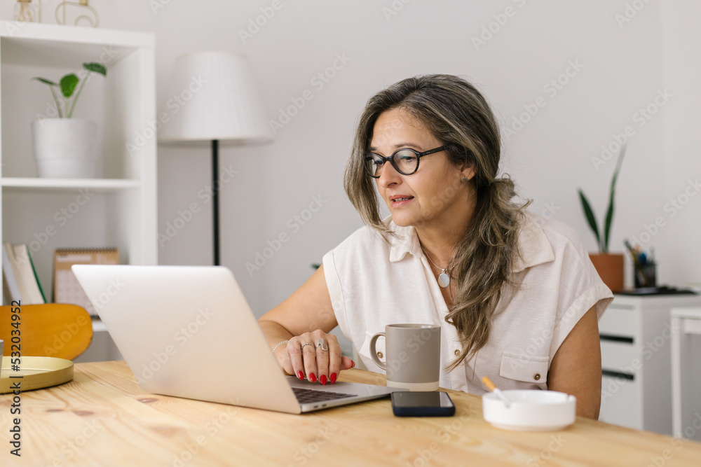 Mature woman working online via computer from home