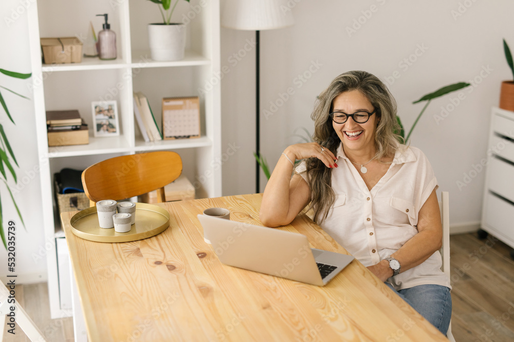Happy woman sitting and working from home via laptop Happy woman sitting and working from home via laptop