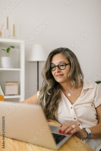 Mature woman browsing via laptop at home
