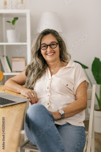 Cheerful portrait of adult businesswoman working from home, smiling and looking to the camera 