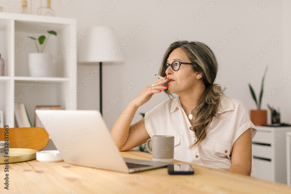 Mature woman sitting and smoking cigarette indoors Mature woman sitting and smoking cigarette indoors