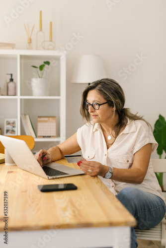 Mature woman shopping online via laptop at home