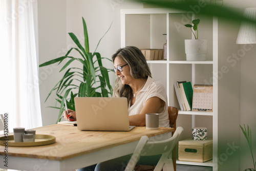 Mature woman woking online from home via laptop