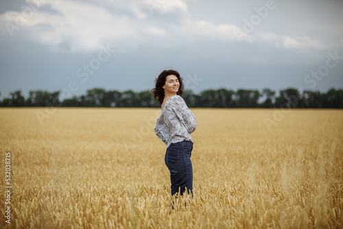 A girl in a field of yellow wheat on the background of a rainy sky