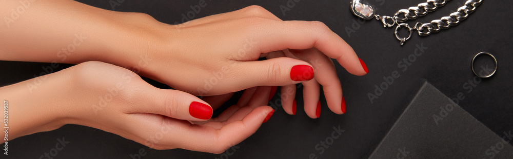 Manicured womans hands with accessories on black background. Halloween manicure, pedicure design trends Manicured womans hands with accessories on black background. Halloween manicure, pedicure design trends