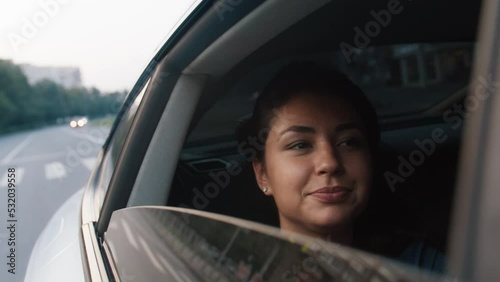 A young beautiful woman rides in a taxi, looks out the open window, enjoys the road. Road, trip, car. Slow motion 4k footage