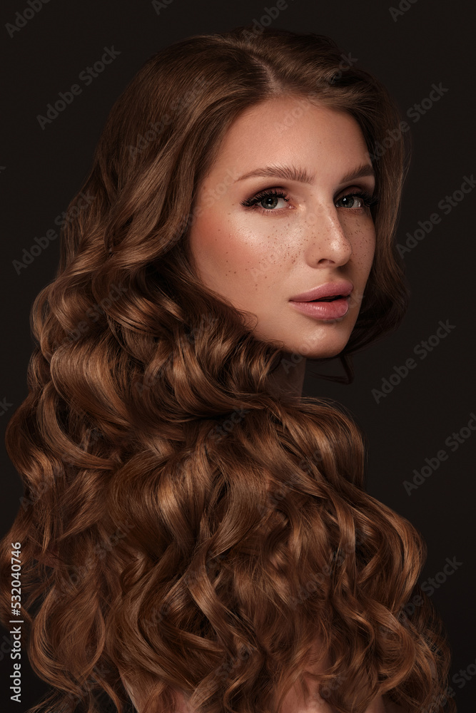 Naklejka premium Beautiful brown-haired girl with a perfectly curls hair, and classic make-up. Beauty face and hair.