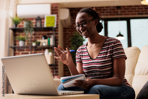 Smiling remote student attending online courses class videoconference, taking notes. E learning, home education lessons, woman watching educational tutorial, writing in notebook photo