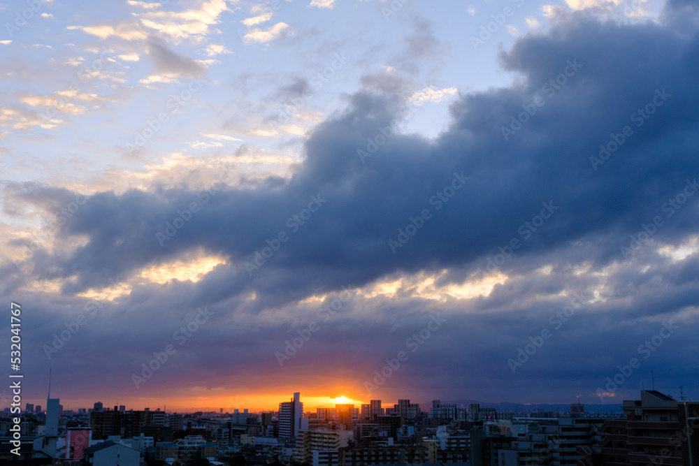 都市の夜明け。東の空に太陽が浮かび辺りをオレンジ色に染める。神戸市東灘区から芦屋市の高層マンション、大阪方面を臨む