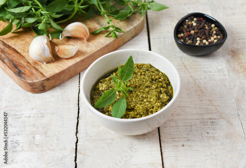 Homemade Italian pesto sauce. Basil, olive oil, pepper, garlic, pine nuts. Top view, wooden background