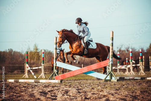 A young girl athlete participates in a show jumping competition. © sergo321