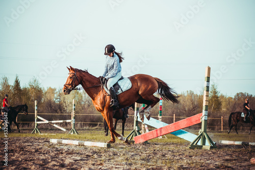 A young girl athlete participates in a show jumping competition.