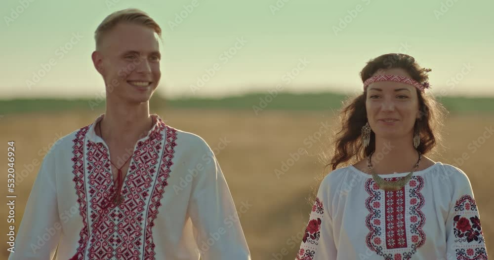 Portrait, happy man and woman in embroidered shirts walking across the field and holding hands. Man and a woman in Ukrainian costumes smile, friendship of peoples. 4k, ProRes Portrait, happy man and woman in embroidered shirts walking across the field and holding hands. Man and a woman in Ukrainian costumes smile, friendship of peoples. 4k, ProRes