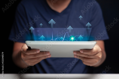 Tablet in hand of a man looking at a holographic digital business growth chart in his home. Small Business Ideas. selective focus on tablet. photo